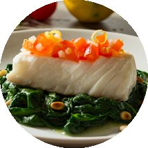 garniertes Fischfilet auf Blattspinat mit Pinienkernen